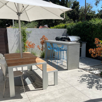 Concrete outdoor kitchen, bar seating, and dining table