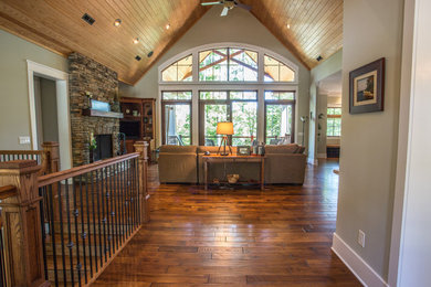 Large arts and crafts open concept medium tone wood floor family room photo with beige walls, a standard fireplace, a stone fireplace and no tv
