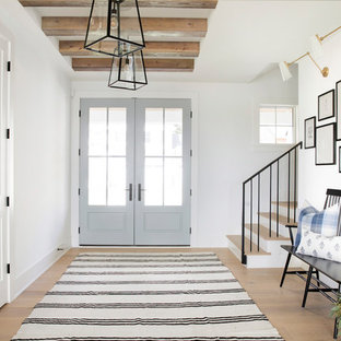 Idée de décoration pour un hall d'entrée champêtre avec un mur blanc, un sol en bois clair, une porte double et une porte en verre.