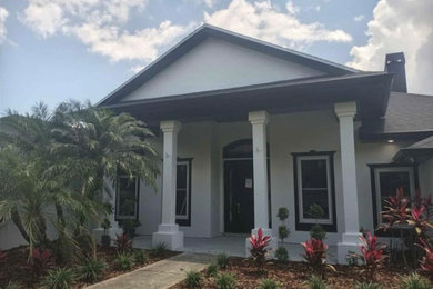 Large trendy white one-story concrete house exterior photo in Orlando with a black roof