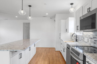 Inspiration for a large southwestern galley light wood floor and brown floor eat-in kitchen remodel in Dallas with a farmhouse sink, shaker cabinets, white cabinets, quartz countertops, gray backsplash, stone tile backsplash, stainless steel appliances, an island and white countertops
