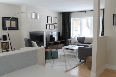 This is an example of a mid-sized midcentury open concept living room in Montreal with grey walls, light hardwood floors, a standard fireplace, a tile fireplace surround and a freestanding tv.
