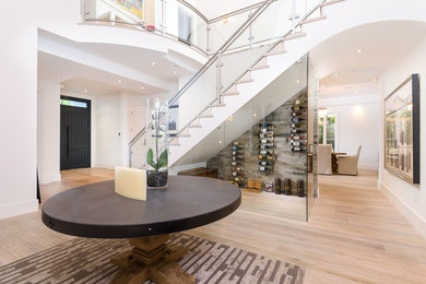 Example of a large trendy light wood floor and beige floor entryway design in Los Angeles with white walls and a black front door