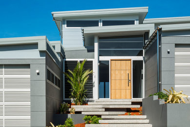 Contemporary front door in Cairns with white walls, porcelain floors, a pivot front door, a medium wood front door and white floor.