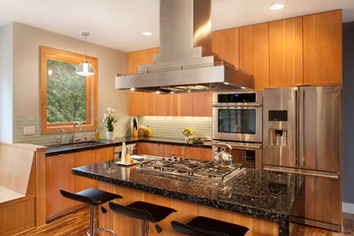 Kitchen - modern medium tone wood floor kitchen idea in Portland with an undermount sink, flat-panel cabinets, medium tone wood cabinets, granite countertops, green backsplash, glass tile backsplash, stainless steel appliances and an island