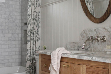 Inspiration for a mid-sized transitional gray tile and marble tile marble floor, gray floor, single-sink and wainscoting bathroom remodel in Toronto with flat-panel cabinets, medium tone wood cabinets, a two-piece toilet, white walls, an undermount sink, marble countertops, a niche and a freestanding vanity