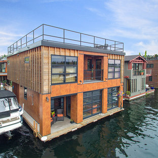 シアトルのインダストリアルスタイルのおしゃれな家の外観 (木材サイディング、陸屋根、戸建、オレンジの外壁) の写真