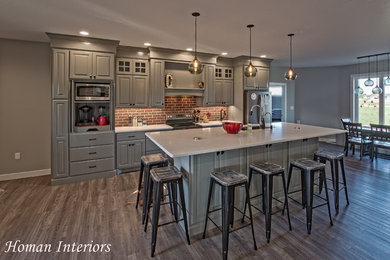 Inspiration for a mid-sized craftsman single-wall medium tone wood floor and gray floor eat-in kitchen remodel in Other with an undermount sink, raised-panel cabinets, gray cabinets, quartz countertops, multicolored backsplash, brick backsplash, stainless steel appliances, an island and white countertops