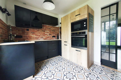 ナントにあるお手頃価格の中くらいなインダストリアルスタイルのおしゃれな独立型キッチン (黒いキャビネット、ラミネートカウンター、ボーダータイルのキッチンパネル、セメントタイルの床) の写真