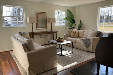Photo of a contemporary living room in DC Metro with beige walls and brown floors.