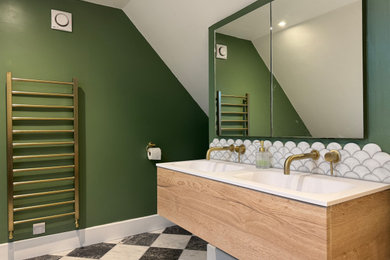 Inspiration for a large contemporary grey and white ensuite half tiled bathroom in Sussex with flat-panel cabinets, light wood cabinets, a freestanding bath, a built-in shower, a two-piece toilet, white tiles, marble tiles, green walls, marble flooring, an integrated sink, solid surface worktops, multi-coloured floors, a hinged door, white worktops, a feature wall, double sinks and a floating vanity unit.