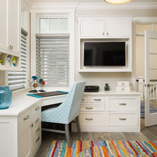 Photo of a coastal study in Grand Rapids with white walls, medium hardwood flooring, a built-in desk and brown floors.