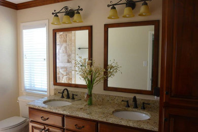 Mid-sized elegant master bathroom photo in Austin with raised-panel cabinets, medium tone wood cabinets, a two-piece toilet, beige walls, an undermount sink and granite countertops