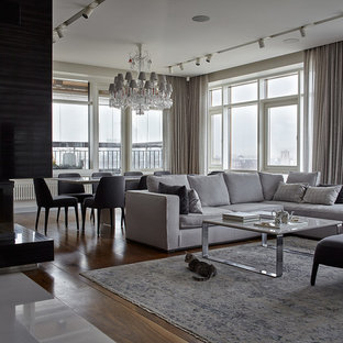 Пример оригинального дизайна интерьера: открытая гостиная комната в современном стиле с бежевыми стенами, паркетным полом среднего тона, камином и коричневым полом