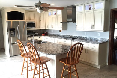 Inspiration for a mid-sized transitional l-shaped porcelain tile enclosed kitchen remodel in DC Metro with an undermount sink, raised-panel cabinets, white cabinets, granite countertops, stainless steel appliances and an island