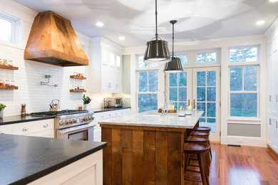 Cottage l-shaped medium tone wood floor kitchen photo in Boston with an undermount sink, shaker cabinets, white cabinets, white backsplash, subway tile backsplash, stainless steel appliances and an island