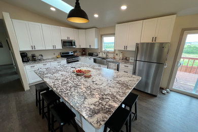 Inspiration for a mid-sized cottage l-shaped laminate floor, gray floor and vaulted ceiling eat-in kitchen remodel in Denver with a farmhouse sink, shaker cabinets, white cabinets, granite countertops, stainless steel appliances, an island and white countertops