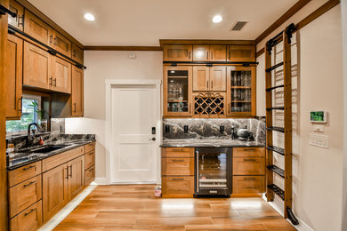 Wet bar - mid-sized l-shaped porcelain tile and brown floor wet bar idea in Miami with an undermount sink, recessed-panel cabinets, medium tone wood cabinets, onyx countertops, stone slab backsplash and brown countertops