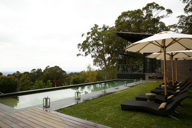 Mid-sized country courtyard rectangular infinity pool in Sydney with natural stone pavers.