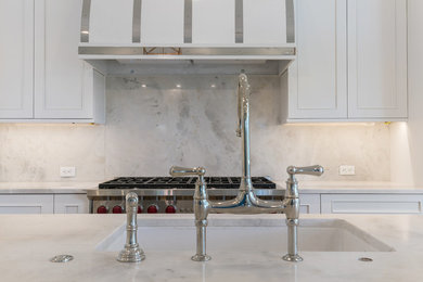 Large transitional l-shaped medium tone wood floor and brown floor open concept kitchen photo in Jacksonville with an undermount sink, shaker cabinets, white cabinets, marble countertops, white backsplash, marble backsplash, stainless steel appliances, an island and white countertops