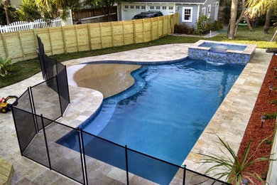 This is an example of a mid-sized beach style backyard custom-shaped lap pool in Jacksonville with a hot tub and natural stone pavers.