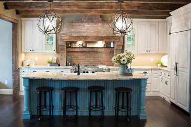 Example of a mountain style l-shaped kitchen design in Cincinnati with raised-panel cabinets and an island