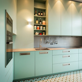 Удачное сочетание для дизайна помещения: маленькая отдельная, угловая кухня в современном стиле с монолитной раковиной, плоскими фасадами, бирюзовыми фасадами, столешницей из нержавеющей стали, серым фартуком, фартуком из металлической плитки, черной техникой, бирюзовым полом и серой столешницей без острова - самое интересное для вас