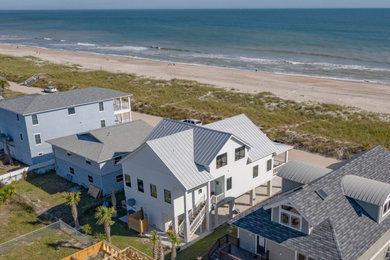 Large beach style white three-story exterior home photo with a metal roof
