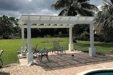 Photo of a mid-sized midcentury backyard patio in Miami with brick pavers and a pergola.