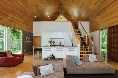 Example of a small trendy galley medium tone wood floor and brown floor open concept kitchen design in Philadelphia with flat-panel cabinets, white cabinets, concrete countertops, paneled appliances and a peninsula