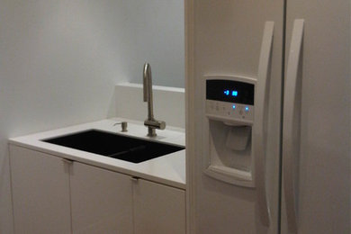 Inspiration for a modern medium tone wood floor kitchen remodel in Toronto with an undermount sink, flat-panel cabinets, white cabinets, solid surface countertops, white appliances and a peninsula