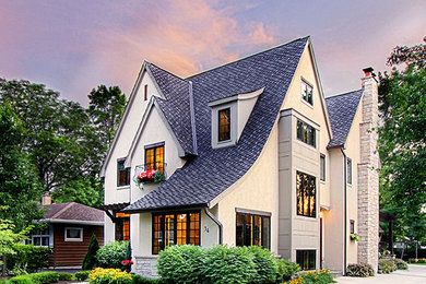 Example of a large classic beige three-story stucco exterior home design in Chicago with a clipped gable roof