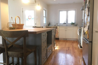 Eat-in kitchen - small farmhouse l-shaped light wood floor and beige floor eat-in kitchen idea in Boston with an undermount sink, shaker cabinets, white cabinets, quartz countertops, white backsplash, subway tile backsplash, stainless steel appliances, an island and white countertops