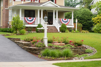 Inspiration for a traditional front yard full sun xeriscape in New York with natural stone pavers and a retaining wall.