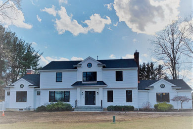 Exemple d'une façade de maison blanche nature en planches et couvre-joints de taille moyenne et à un étage avec un toit en shingle et un toit noir.