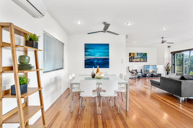 This is an example of a large contemporary dining room in Gold Coast - Tweed with white walls, light hardwood floors and no fireplace.