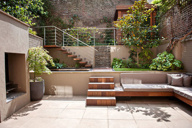 This is an example of a small contemporary backyard patio in London with concrete pavers, no cover and with fireplace.