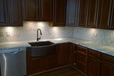 Inspiration for a large modern l-shaped dark wood floor eat-in kitchen remodel in Other with a farmhouse sink, raised-panel cabinets, dark wood cabinets, granite countertops, gray backsplash, stone tile backsplash, stainless steel appliances and an island