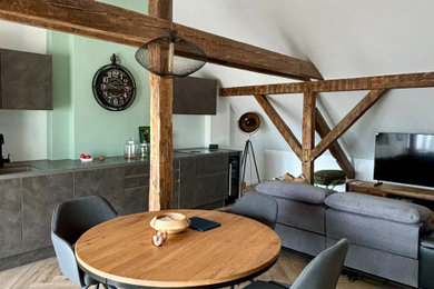 Exemple d'une salle à manger ouverte sur le salon chic de taille moyenne avec un mur vert, parquet clair, aucune cheminée, un sol beige et poutres apparentes.