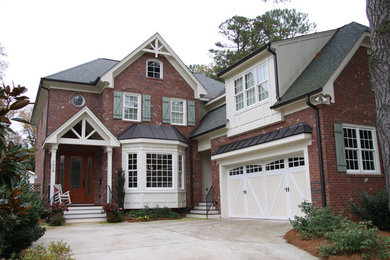 Example of a two-story brick house exterior design in Raleigh with a shingle roof