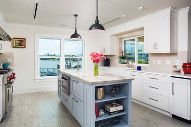 Mid-sized minimalist u-shaped light wood floor open concept kitchen photo in Miami with shaker cabinets, white cabinets, quartz countertops, beige backsplash, stone tile backsplash, stainless steel appliances, an island and a farmhouse sink
