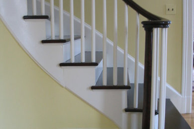 Diseño de escalera curva tradicional de tamaño medio con barandilla de madera, escalones de madera pintada y contrahuellas de madera pintada