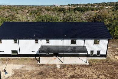 Large white two-story metal exterior home photo in Austin with a metal roof and a black roof