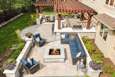 Inspiration for a large traditional backyard patio in Chicago with an outdoor kitchen, brick pavers and a pergola.