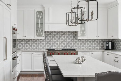 This is an example of a large transitional u-shaped eat-in kitchen in Chicago with shaker cabinets, grey cabinets, quartz benchtops, grey splashback, mosaic tile splashback, stainless steel appliances, with island, brown floor, white benchtop and medium hardwood floors.
