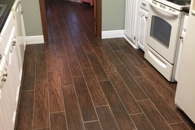 Elegant galley porcelain tile enclosed kitchen photo in Austin with a drop-in sink, raised-panel cabinets, white cabinets, quartz countertops, black backsplash, stone slab backsplash, white appliances and no island