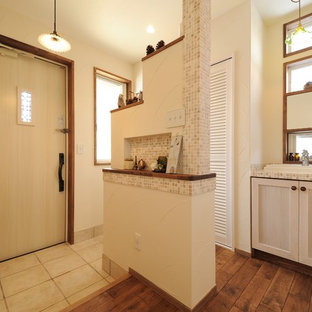 他の地域の片開きドアアジアンスタイルのおしゃれな玄関ホール (白い壁、淡色木目調のドア、ベージュの床) の写真