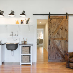 This is an example of a large country home studio in Boston with white walls, medium hardwood floors, no fireplace and a freestanding desk.