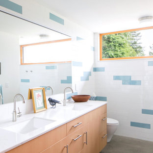 Immagine di una stanza da bagno moderna con ante lisce, ante in legno chiaro, piastrelle blu, piastrelle bianche, pavimento in cemento, lavabo sottopiano, pavimento grigio e top bianco