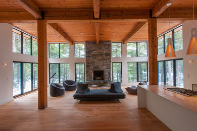 Large trendy formal and open concept medium tone wood floor living room photo in Toronto with white walls, a standard fireplace, a stone fireplace and no tv